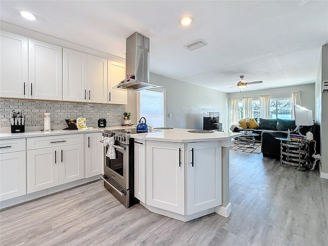 1859 Oklahoma Ave NE, Saint Petersburg, FL 33703 - kitchen featuring electric stove, island exhaust hood, a peninsula, light wood-style flooring, and light countertops