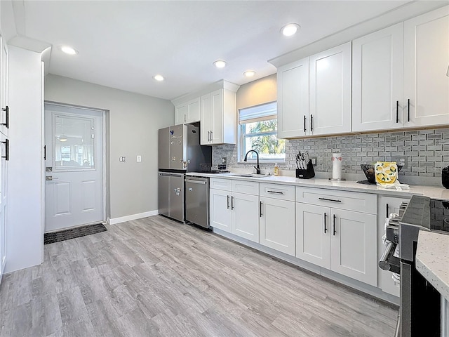 1859 Oklahoma Ave NE, Saint Petersburg, FL 33703 - kitchen with appliances with stainless steel finishes, a sink, backsplash, light wood-style flooring, and white cabinets