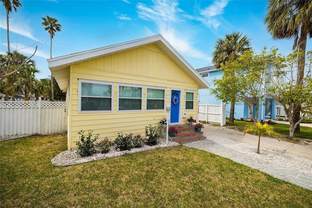 bungalow-style home with a front yard and fence