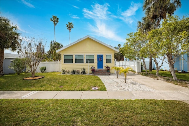 view of front of property with entry steps, fence, and a front lawn