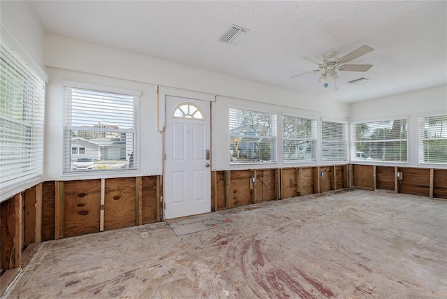 unfurnished sunroom with a ceiling fan and visible vents