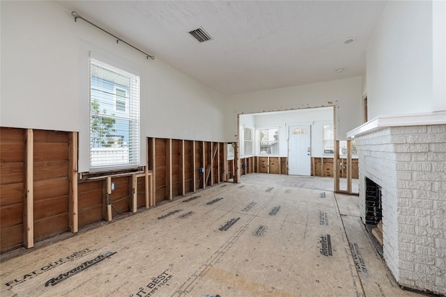 unfurnished living room featuring a brick fireplace and visible vents