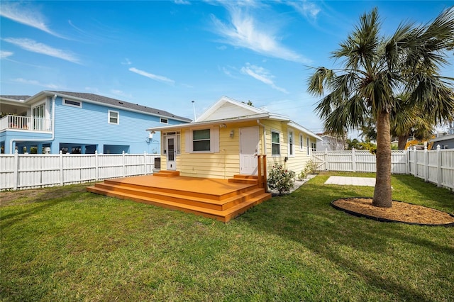 rear view of house with a fenced backyard, a lawn, and a deck