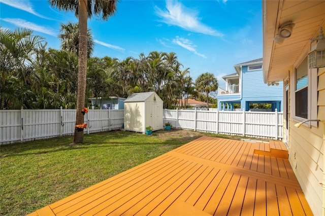 wooden deck featuring a storage shed, a yard, an outbuilding, and a fenced backyard