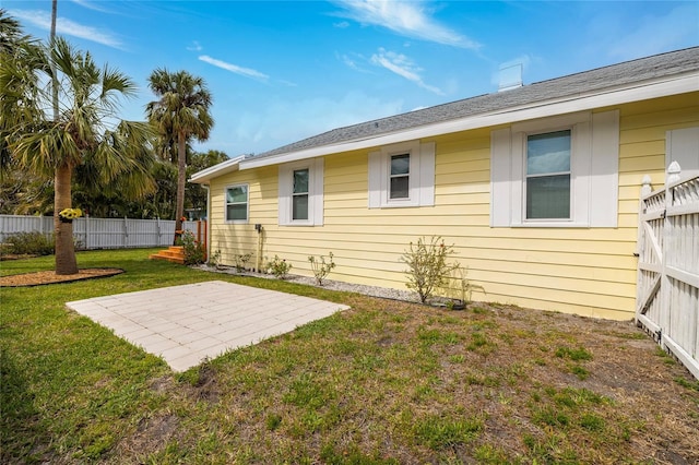 rear view of property featuring a lawn, a patio area, and fence