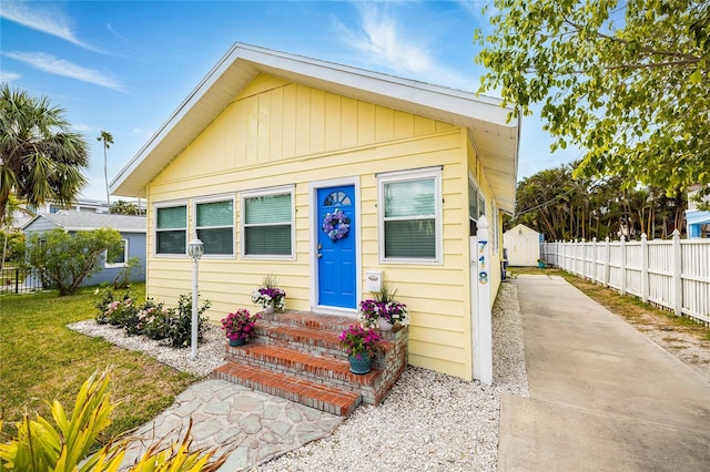 bungalow with fence, an outdoor structure, driveway, and a shed