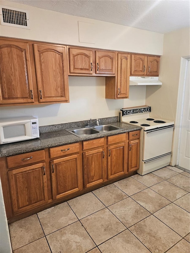 kitchen featuring visible vents, brown cabinetry, a sink, white appliances, and under cabinet range hood