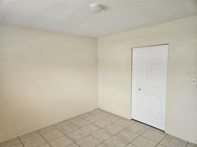 unfurnished room featuring light tile patterned floors and baseboards