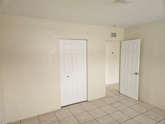 unfurnished bedroom featuring light tile patterned floors, visible vents, and baseboards