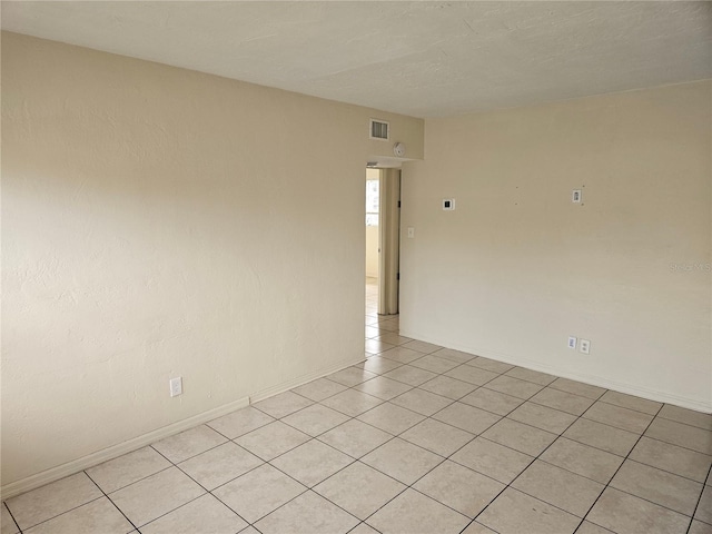 empty room with visible vents, baseboards, and light tile patterned flooring