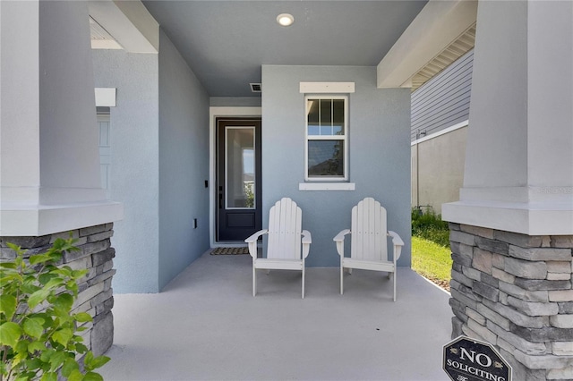 view of exterior entry featuring a patio area and stucco siding