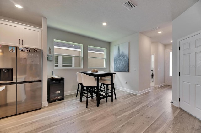 dining space with wine cooler, light wood finished floors, recessed lighting, visible vents, and baseboards