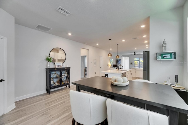 kitchen with visible vents, light wood-style flooring, a kitchen island with sink, a sink, and recessed lighting