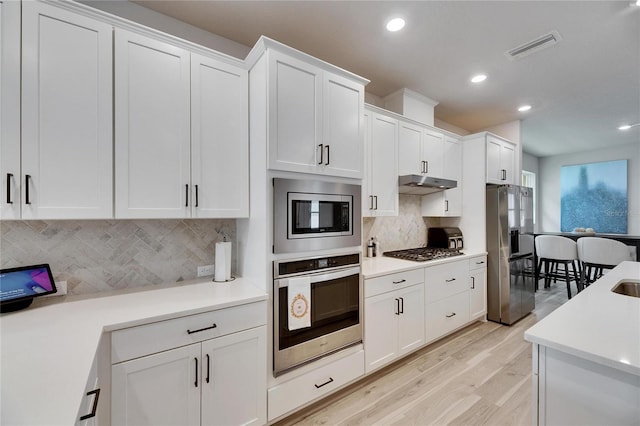 kitchen with stainless steel appliances, light countertops, visible vents, white cabinetry, and under cabinet range hood