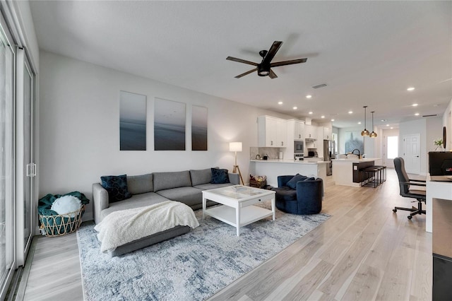 living room with ceiling fan, light wood-type flooring, visible vents, and recessed lighting