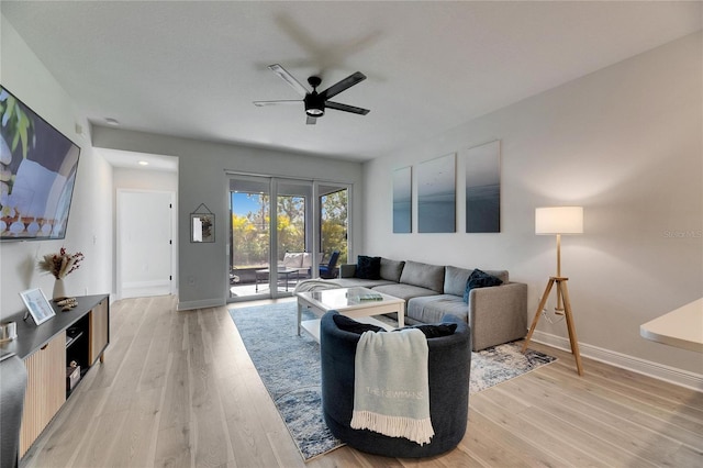 living room with light wood-style floors, baseboards, and a ceiling fan