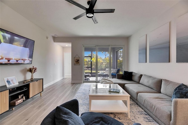 living room featuring wood finished floors, a ceiling fan, and baseboards