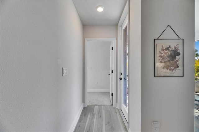 corridor with baseboards and light wood-style floors