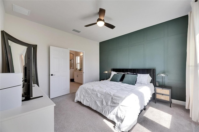 bedroom with a ceiling fan, light carpet, a decorative wall, and visible vents