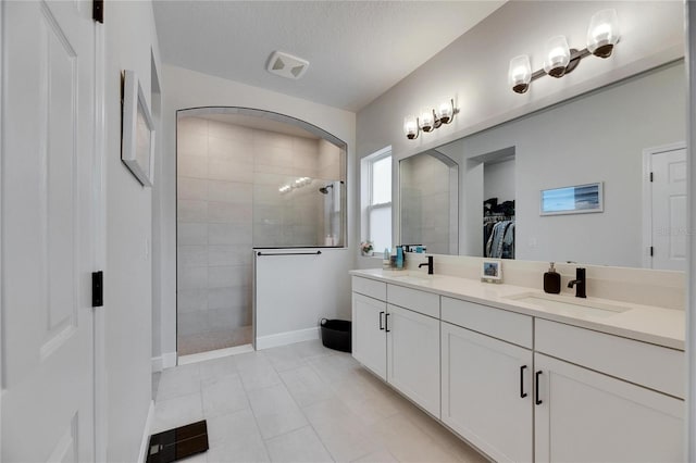 full bath with a walk in closet, double vanity, a sink, and walk in shower