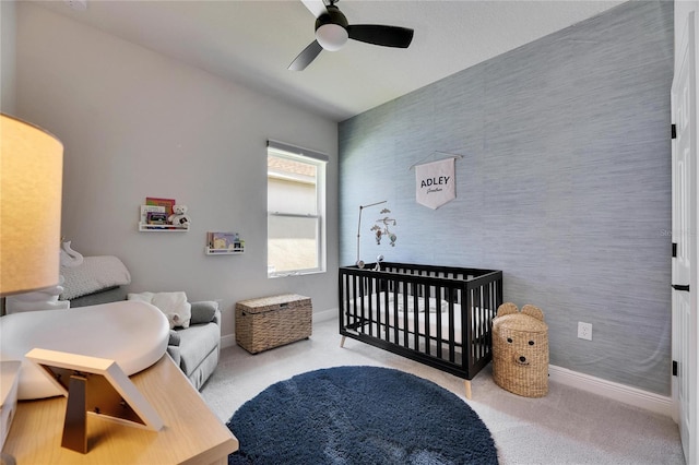 bedroom with carpet floors, an accent wall, baseboards, a nursery area, and wallpapered walls