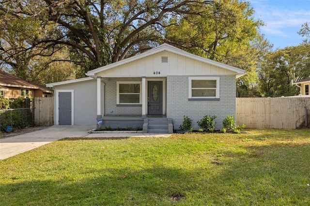 bungalow with fence, a front lawn, a porch, board and batten siding, and brick siding