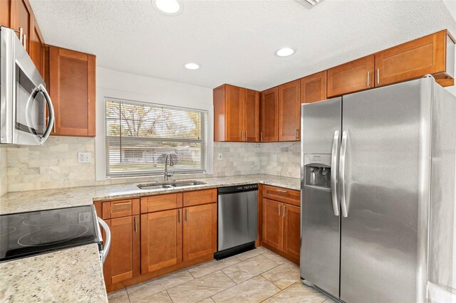 kitchen featuring appliances with stainless steel finishes, backsplash, a sink, and brown cabinets