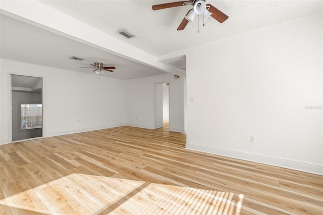 empty room featuring light wood-style floors, baseboards, a ceiling fan, and a textured ceiling