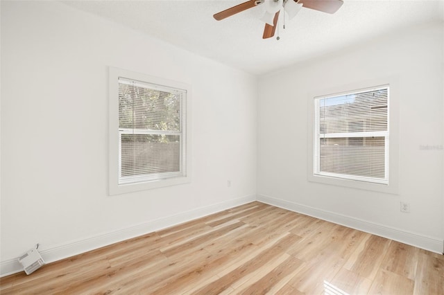 spare room with ceiling fan, light wood-style flooring, and baseboards