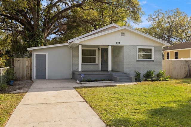 bungalow with brick siding, a porch, fence, and a front yard