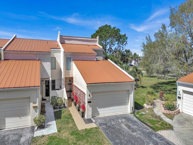 view of front facade featuring a standing seam roof, a detached garage, metal roof, and stucco siding