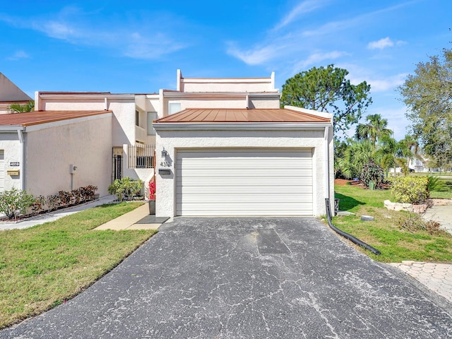 view of front of house with an attached garage, a front lawn, aphalt driveway, and stucco siding