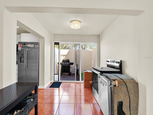 interior space featuring light tile patterned floors, white cabinetry, appliances with stainless steel finishes, and baseboards