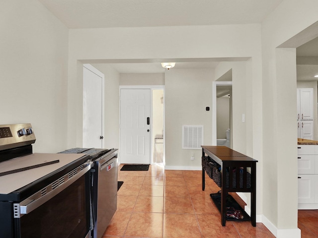 kitchen featuring light tile patterned floors, appliances with stainless steel finishes, visible vents, and baseboards