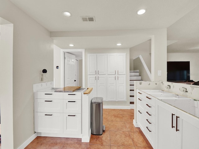 kitchen with recessed lighting, a sink, visible vents, baseboards, and white cabinetry