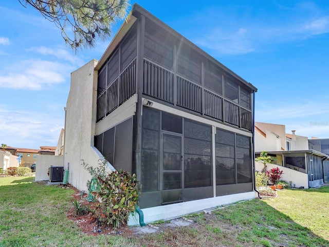 view of side of property featuring a sunroom, central AC, and a yard