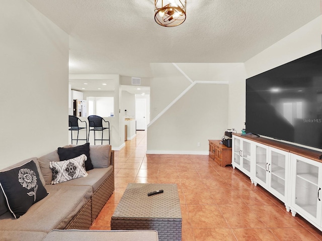 living area featuring baseboards, visible vents, a textured ceiling, and light tile patterned flooring