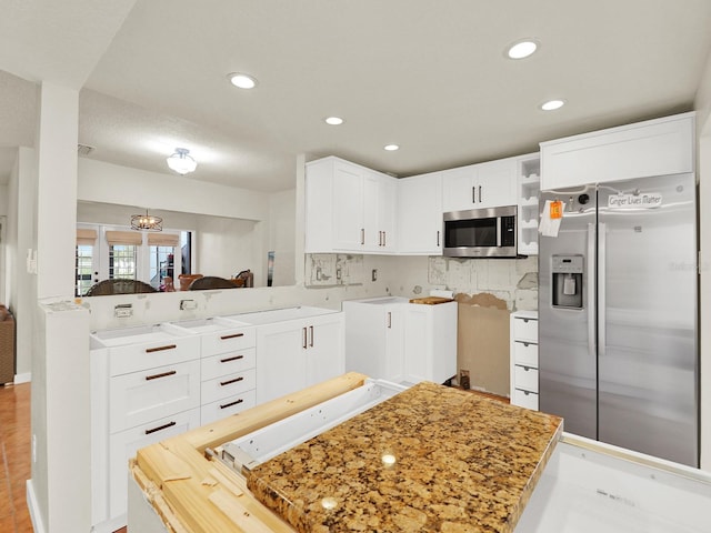 kitchen featuring recessed lighting, stainless steel appliances, a peninsula, white cabinets, and tasteful backsplash