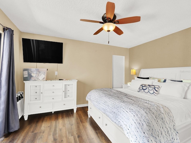 bedroom featuring ceiling fan, a textured ceiling, baseboards, and dark wood-type flooring