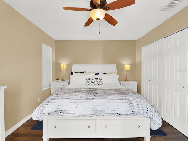 bedroom with dark wood-style flooring, a closet, visible vents, and baseboards