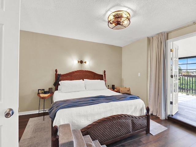 bedroom with access to exterior, a textured ceiling, baseboards, and wood finished floors