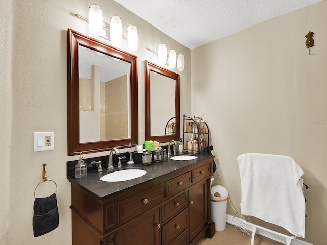 full bathroom featuring double vanity, tile patterned flooring, a textured ceiling, and a sink