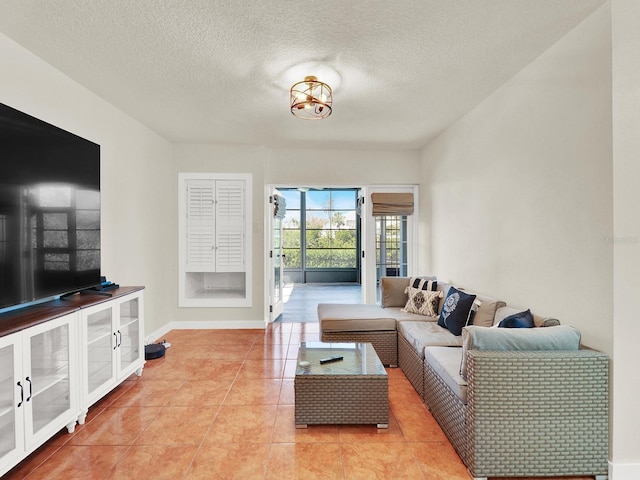 living area featuring light tile patterned floors, a textured ceiling, and baseboards