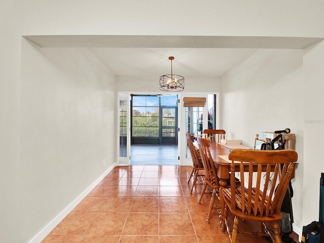 dining area featuring a chandelier, light tile patterned flooring, and baseboards