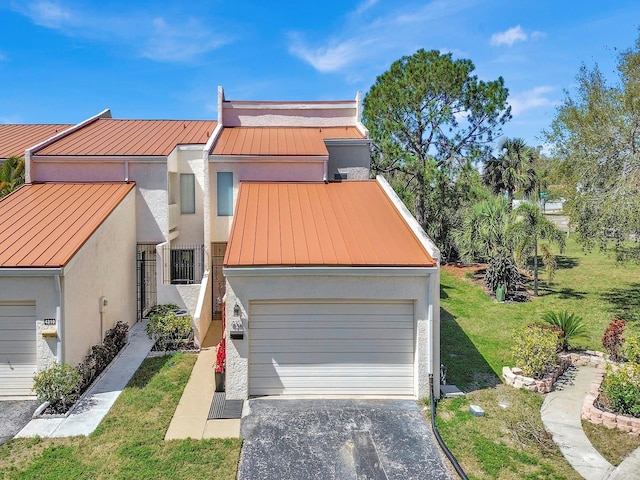 view of property with metal roof, a garage, stucco siding, a standing seam roof, and a front yard