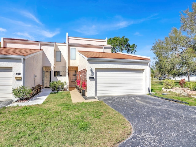 view of front of property featuring a garage, driveway, a front yard, and stucco siding