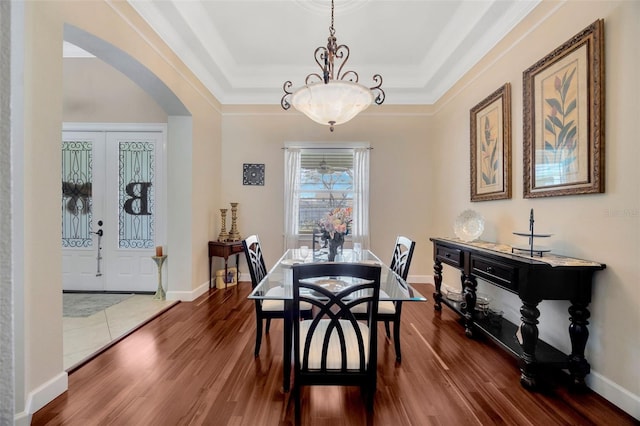 4411 Culbreath Rd, Valrico, FL 33596 - dining room featuring baseboards, a raised ceiling, arched walkways, and dark wood-style flooring