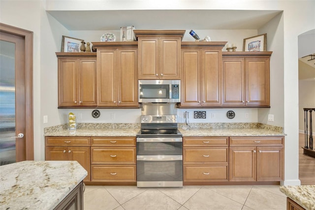 4411 Culbreath Rd, Valrico, FL 33596 - kitchen featuring light tile patterned floors, light stone counters, brown cabinets, and appliances with stainless steel finishes