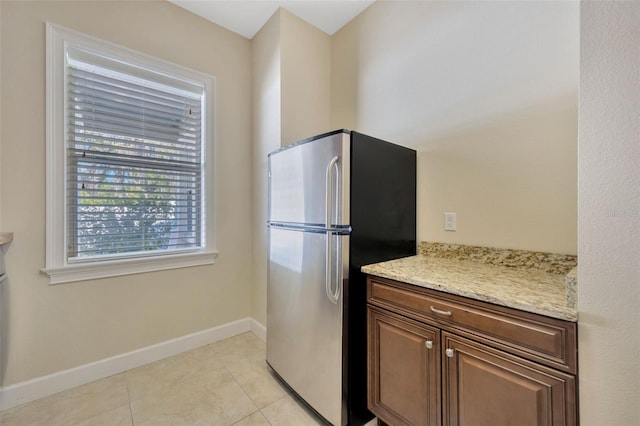 4411 Culbreath Rd, Valrico, FL 33596 - kitchen featuring light tile patterned floors, baseboards, light stone countertops, and freestanding refrigerator