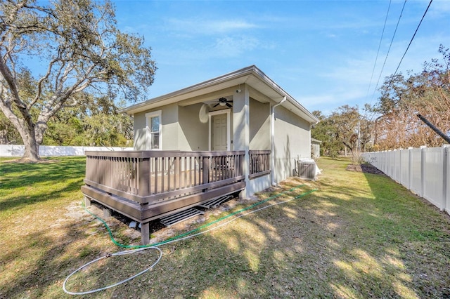 4411 Culbreath Rd, Valrico, FL 33596 - rear view of house featuring fence, a wooden deck, stucco siding, a lawn, and a ceiling fan